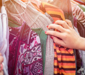 a hand going through a clothing rack at thrift store